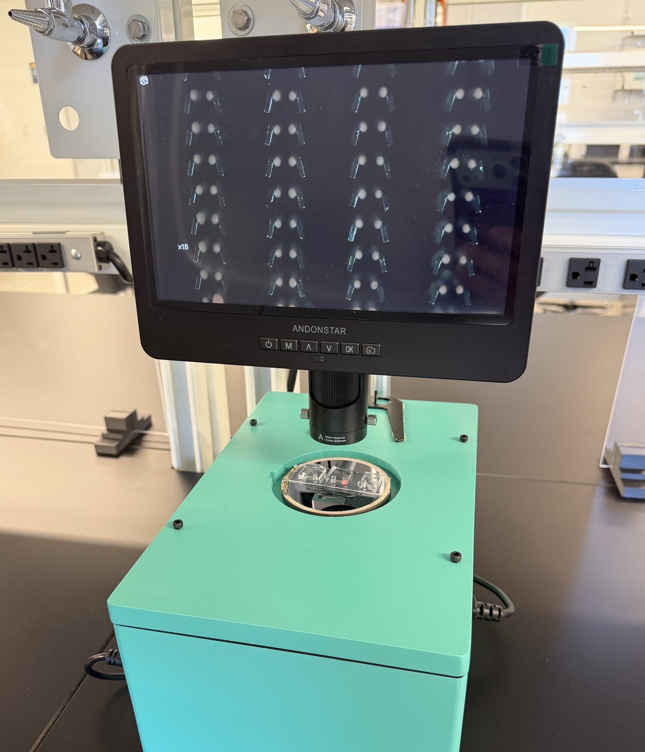 An EchoBox unit on a laboratory bench, with an AESOP chip loaded in the stage and microvortices visible on the monitor above
